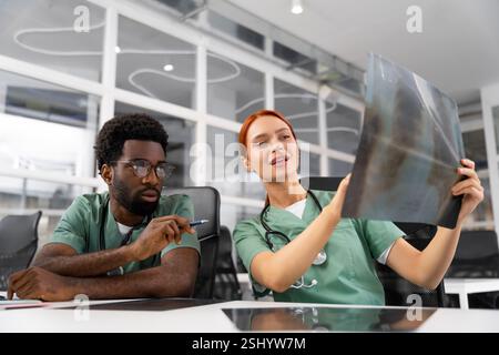 Diverse doctors collaborating on surgery discussing diagnosis and reading X-ray Stock Photo