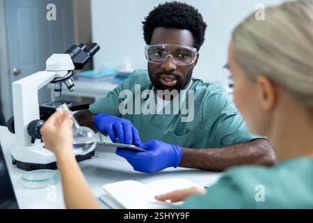 Woman and man doctors studying biochemistry using advanced technology in laboratory Stock Photo