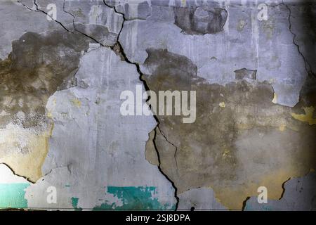 Interior of an old, dilapidated house The cracked wall has traces of old plaster and paint mould can be seen growing on the damp exterior wall Photogr Stock Photo