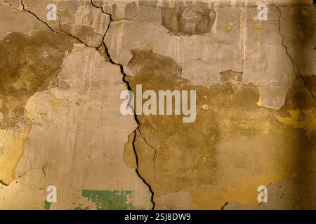 Interior of an old, dilapidated house The cracked wall has traces of old plaster and paint mould can be seen growing on the damp exterior wall Photogr Stock Photo