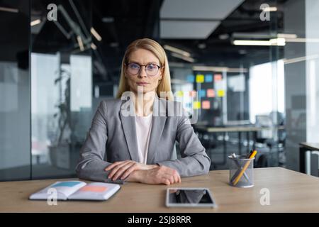 Successful confident female boss at workplace looking at camera, serious and concentrated. Businesswoman inside office at workplace. Stock Photo