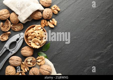 Fresh ripe walnuts, shells and nutcracker on black table, flat lay. Space for text Stock Photo
