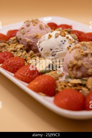 A plate of ice cream scoops with strawberries and granola for ice cream for breakfast day Stock Photo