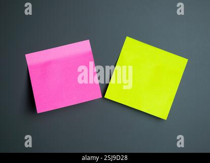 Two colorful sticky notes in pink and green sit on a grey surface Stock Photo