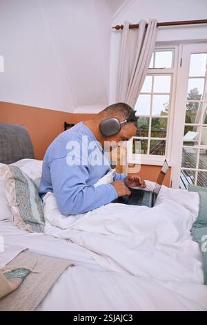 Man with Down Syndrome using laptop in bed Stock Photo