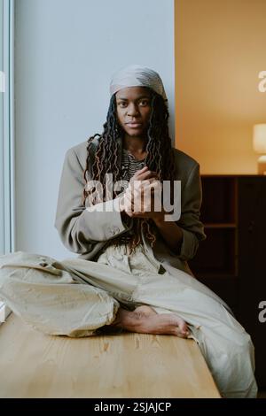 African american woman relaxed with hands on head sitting on sofa at ...