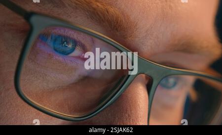 Close up cropped view details male eyes in eyeglasses eyewear glasses Caucasian man business guy businessman night gamer programmer looking laptop Stock Photo