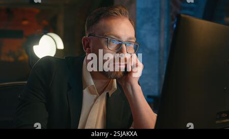 Tired exhausted fatigued late time boring working businessman stressed overworked Caucasian business man employer typing computer online guy male work Stock Photo