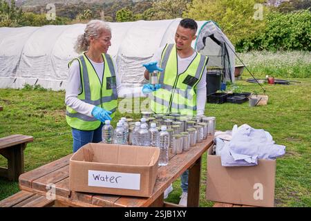 Two volunteers packaging donation boxes at table outdoors Stock Photo