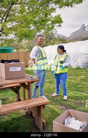 Two volunteers standing next to donation boxes at table outdoors Stock Photo