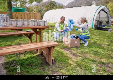 Two volunteers packaging donation boxes at table outdoors Stock Photo