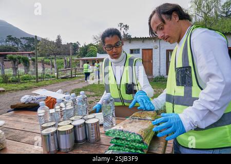 Two volunteers packaging donation boxes at table outdoors Stock Photo