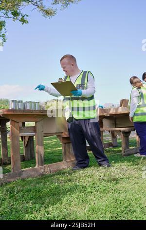 Two volunteers packaging donation boxes at table outdoors Stock Photo