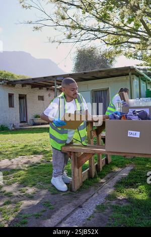 Two volunteers packaging donation boxes at table outdoors Stock Photo