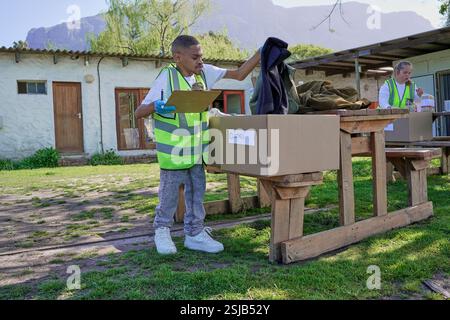 Two volunteers packaging donation boxes at table outdoors Stock Photo