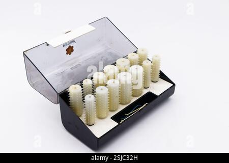Set of vintage white Carmen plastic heated hair curlers rollers in an open black storage case on a white background Stock Photo