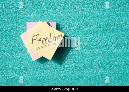 A handwritten "Freedom" message on a sticky note against a bright green background, conveying positivity, hope, and limitless possibilities. Stock Photo