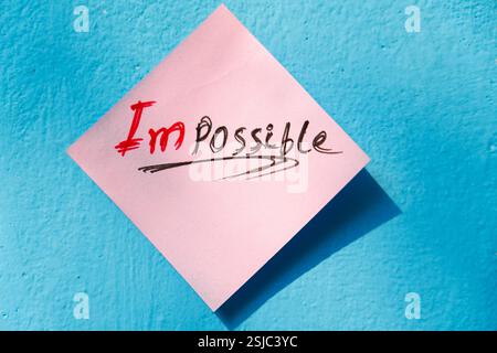 Close-up of a motivational note transforming "Impossible" into "I'm Possible," encouraging resilience. Stock Photo