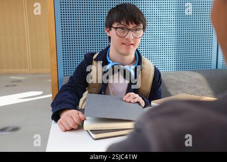 Man with Down Syndrome sitting at table Stock Photo