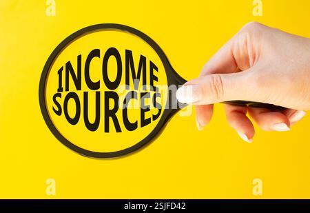 Income Sources symbol. Magnifying Glass with Concept word Income Sources. Beautiful yellow background. Businessman hand. Business and Income Sources c Stock Photo
