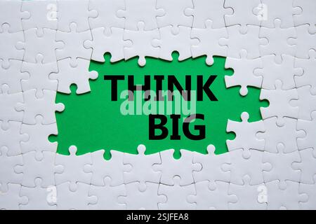 Think big symbol. White puzzle with words Think big. Beautiful green background. Business and Think big concept. Copy space. Stock Photo