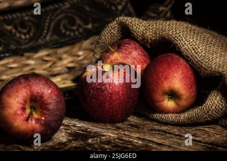 Fresh red apples on wooden rustic table with jute background. Stock Photo