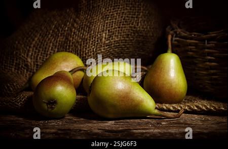 Fresh thigh pears on wooden rustic table with jute background. Stock Photo