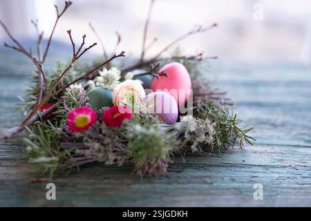 Easter eggs decorated with colorful spring flowers on old rustic wood surface. Stock Photo