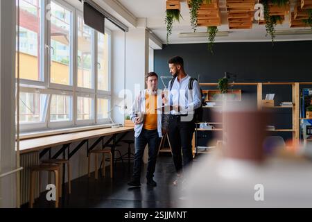 Young man with Down syndrome and his teacher talking while walking down the school hallway. Stock Photo