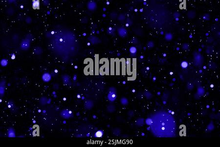 Vibrant blue glowing particles floating against a dark background Stock Photo