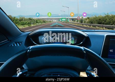 Futuristic smart car concept – an electric vehicle on the road with an augmented navigation system showing EV chargers, parking spots, shopping, and d Stock Photo