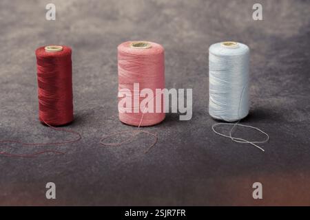 Close-up of three spools of colored sewing thread with out-of-focus background and copy space Stock Photo