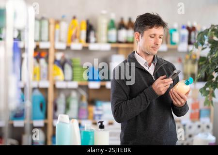 Middle-aged woman scanning QR-code on detergent at supermarket Stock Photo