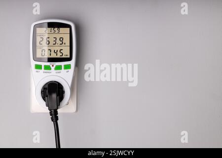 Energy Meter Measuring Power Consumption from Plugged in Device Stock Photo