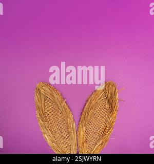 Bunny rabbit ears made of natural plants material on pastel purple background. Easter minimal concept. Flat lay. Stock Photo