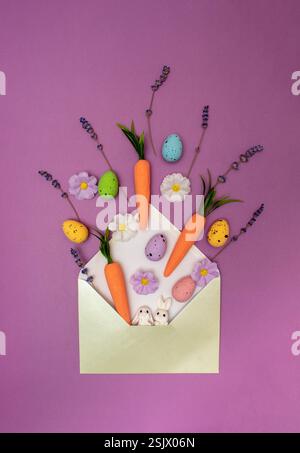 Spring flowers, Easter eggs and carrots coming out of envelope. Spring nature concept. Easter holiday background idea. Stock Photo