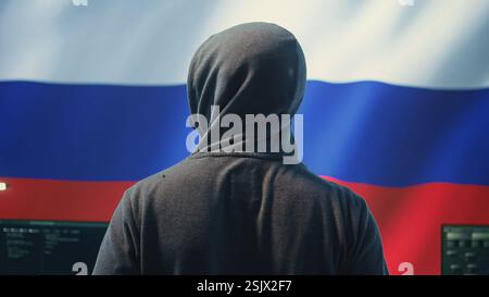 Expert in governmental hacking room with a Russian flag on big screen, individual in cyberwarfare and propaganda. Russian federation hacker works on sabotage and political manipulation. Camera B. Stock Photo