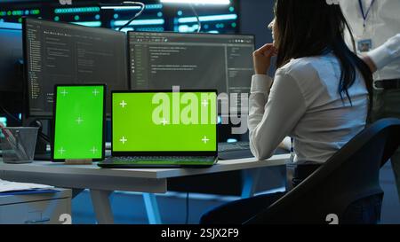 Engineers in data center monitoring security threats using chroma key devices. Experts using isolated screen tablet and laptop, ensuring compliance with regulations, camera A Stock Photo