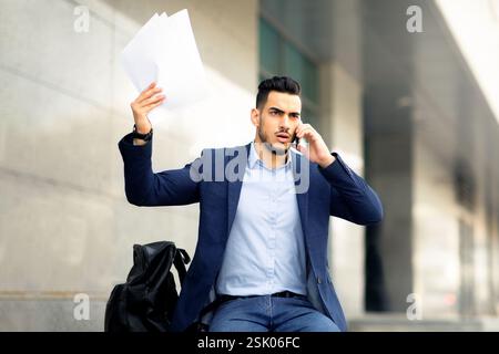 Angry middle-eastern businessman having phone conversation on the street Stock Photo