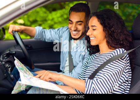 Happy middle-eastern couple sitting in car, planning journey Stock Photo