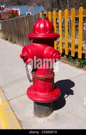 A bright red-painted fire hydrant in a side street in Manitou Springs, Colorado, USA. Such hydrants, which provide convenient sources of water for fire crews, are quite common on American streets, even iconic. Stock Photo