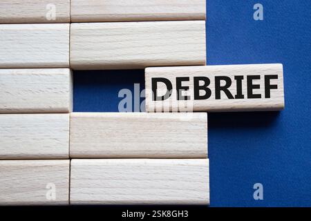 Debrief symbol. Concept word Debrief on wooden blocks. Beautiful deep blue background. Business and Debrief concept. Copy space. Stock Photo