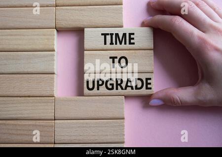 Time to Upgrade symbol. Concept words Time to Upgrade on wooden blocks. Businessman hand. Beautiful pink background. Business and Time to Upgrade conc Stock Photo