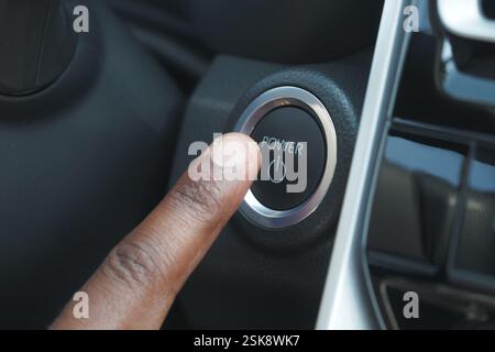 Finger pressing power button in modern vehicle interior Stock Photo