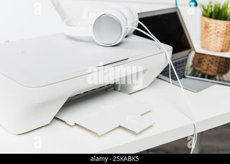 Modern workspace with printer and laptop featuring headphones on a clean desk setup Stock Photo