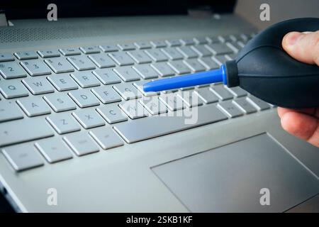 Cleaning computer with blower pump. Blowing debris from under the buttons on the keyboard with a special pear. using air bulb Stock Photo