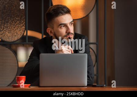 A young business man looking away and thinking in the office. Stock Photo