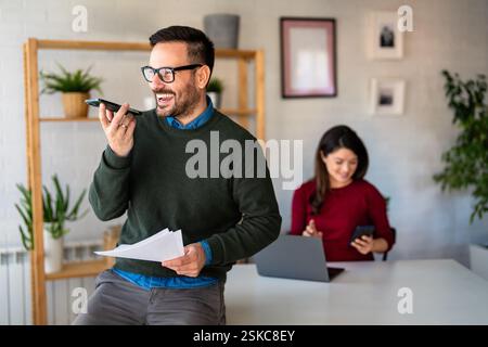 Happy middle aged business man executive using mobile cell phone in office. Stock Photo