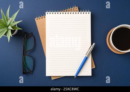 Top view of a workspace with a blank notebook, pen, glasses, coffee, and plant Stock Photo