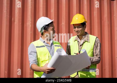 Engineers reviewing construction plans and discussing logistics on-site. Stock Photo